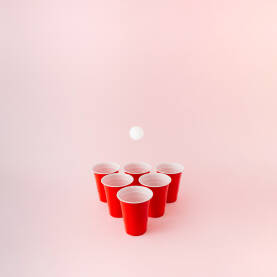 Šest crvenih plastičnih čaša Šest crvenih plastičnih čaša za beer pong igru s bijelom lopticom koja lebdi iznad.
