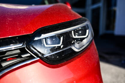 Far automobila Far automobila, detalj. Prednja svjetla crvenog automobila na parkingu u gradu.
