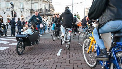 Grupa ljudi vozi bicikle u Amsterdamu Amsterdam, Nizozemska: Grupa biciklista vozi bicikle po ulici. Biciklizam u gradu. Ljudi koriste bicikle za vožnju.