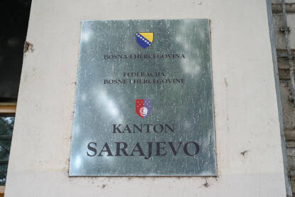 Službena tabla i zastave na zgradi Skupštine Kantona Sarajevo. Tabla s nazivom institucije i zastavama na zgradi Skupštine Kantona Sarajevo.