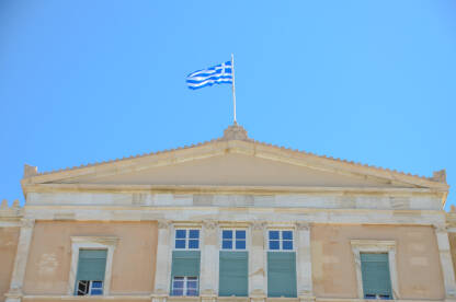 Atina, Grčka: Zgrada Helenskog parlamenta. Zastava Grčke. Stara kraljevska palata na trgu Sintagma, trenutno sjedište Grčkog parlamenta. Ljudi ispred institucije.