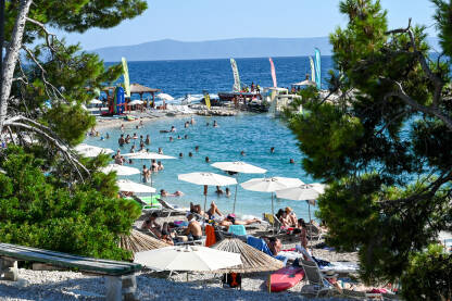 Makarska, Hrvatska: Turisti na plaži i u moru. Makarska, Hrvatska: Turisti na plaži i u moru. Ljetni godišnji odmori. Obala Jadraskog mora ljeti. Turistička sezona. Ljudi se sunčaju i kupaju.