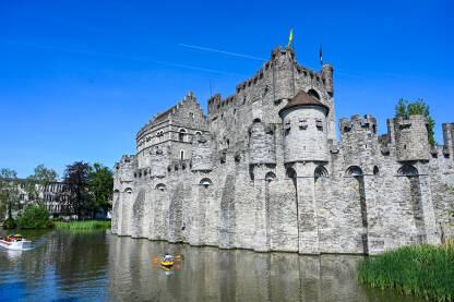 Gent, Belgija: Dvorac uz rijeku. Turisti Gent, Belgija: Dvorac uz rijeku u centru grada. Turisti na čamcima na rijeci.