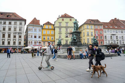 Graz, Austrija: Grupa ljudi na glavnom trgu u centru grada. Graz, Austrija: Grupa ljudi na glavnom trgu u centru grada. Historijske zgrade na glavnom trgu ili Hauptplatzu. Stari grad Graz. Erzherzog-Johann-Brunnen fontana.