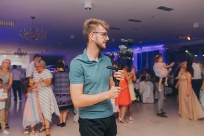 Mladi videograf sa gimbalom u rukama Mladi videograf sa gimbalom u rukama na svadbi / vjenčanju
