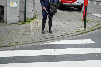 Slabovidna ili slijepa osoba prelazi ulicu uz pomoć bijelog štapa. Slijepa žena hoda ulicom koristeći bijeli štap.