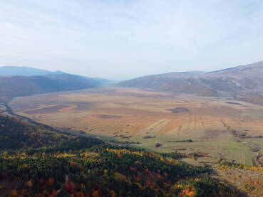 Snimak iz zraka dronom na kraško polje između planina. Glamočko polje, Bosna i Hercegovina. Kraška ravnica okružena planinama.