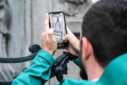 Bruxelles, Belgija. Turist fotografira skulpturu u gradu. Bruxelles, Belgija. Turist fotografira Maneken Pis, simbol Brisela. Poznata znamenitost, skulptura od bronzane fontane u centru grada.