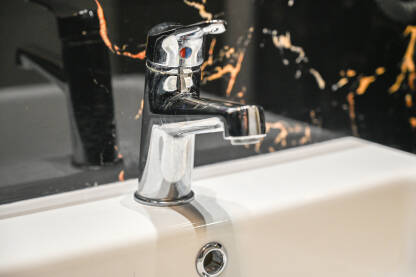 Slavina u kupatilu Slavina u kupaonici u stanu. Bijeli lavabo i slavina za vodu u hotelskoj sobi. Umivaonik i slavina.