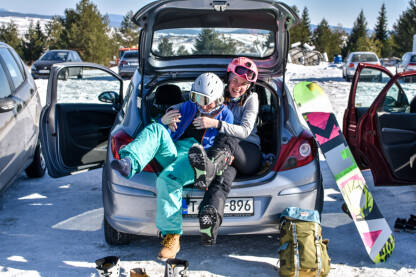 Spremanje za stazu Djevojke se spremaju za ski stazu. Oblačenje ski opreme na parkingu u gepeku. Skijalište Kupres.