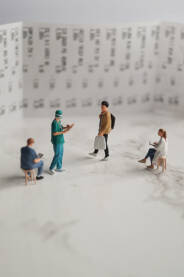 Figurice doktora i kupca sa kesom ispred velikog računa.