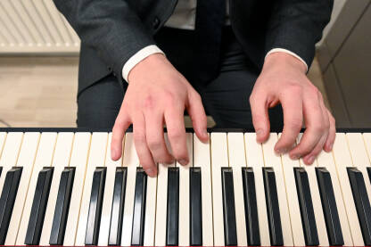 Muškarac svira na klaviru Čovjek svira klavir. Ruke muzičara. Električni piano. Sviranje muzičkog instrumenta u crkvi. Pijanist za klavijaturom.