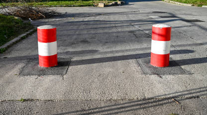 Stubići na ulici, zabranjen prolaz Prugasti crveno-bijeli stupovi na asfaltnoj cesti. Barijera na ulici u gradu. Kontrola ulaza automobila.