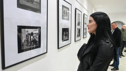 Djevojka gleda fotografije na izložbi. Djevojka gleda fotografije na izložbi. Izložba fotografija u zatvorenom prostoru. Posjetioci izložbe fotografija u galeriji.