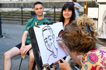 Ulična umjetnost. Žena crta portret para. Ulična umjetnost. Žena crta portret para. Umjetnica crta karikature turista.