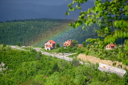 Duga iznad kuća u planini.