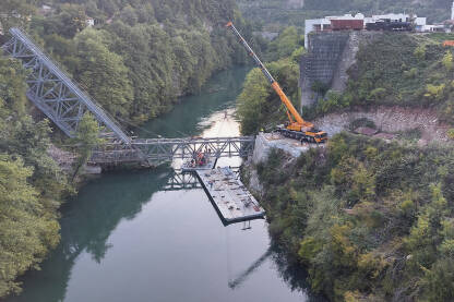 Montaža dijela konstrukcije mosta, iznad rijeke Neretve, uz korištenje velike dizalice.