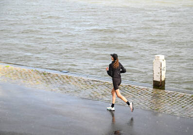 Žena trči po kiši. Djevojka trenira. Trčanje.