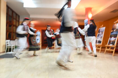 Muškarci i djevojke u tradicionalnoj narodnoj nošnji plešu. Zamućena fotografija grupe ljudi koji plešu. Muškarci i djevojke u tradicionalnoj narodnoj nošnji plešu. Tradicionalni ples. Kolo je južnoslovenski ples koji se izvodi na priredbama.