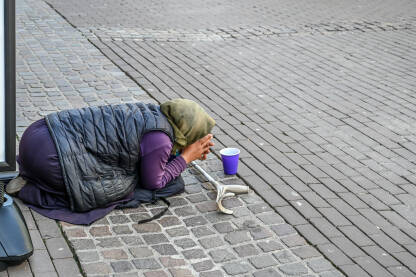 Žena prosi na ulici Žena prosi na ulici. Siromašna beskućnica prosi novac u gradu. Društveni problem.