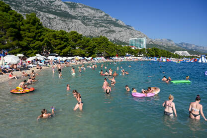 Plaža u Makarskoj puna ljudi Turisti na moru. Ljudi se kupaju i sunčaju u Jadranskom moru. Ljetni odmor. Grupa turista na plaži tokom toplog ljetnog dana. Makarska, Hrvatska.