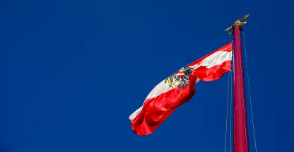 Nacionalna zastava Austrije s grbom. Austrijska zastava na jarbolu. Zastava Austrije s amblemom orla.