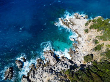 Prekrasna prirodna stjenovita plaža i more ljeti. Valovi se lome na plaži, snimak dronom.