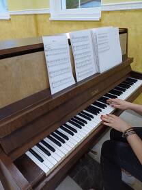 Petrof klavir sa notama Petrof klavir na kojem se nalaze note. Djevojka sa crvenim lakom na noktima svira klavir. Stari klavir koji još može da stvara muziku.
