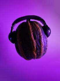 Tikva sa slušalicama Izdvojena tikva sa crnim slušalicama na neonskoj ljubičastoj podlozi, purple neon background. Kreativni minimalistički koncept - muzika, muzički, muzičar, disco, DJ...