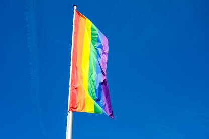 LGBTIQ zastava LGBTIQ zastava se vijori na vjetru na jarbolu u gradu. Simbol LGBT zajednice i društvenog pokreta. Simbol lezbejske, gej, biseksualne, transrodne i queer zajednice.