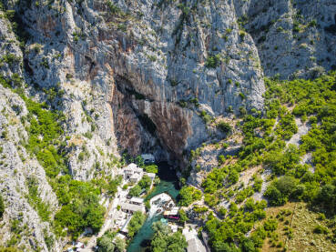 Stijena Ogoljena stijena slikana dronom sa jezerom u podnožiju i niskim ratinjem