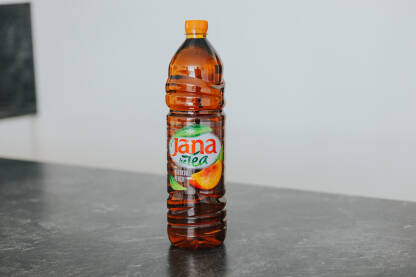 Jana ledeni čaj od breskve na sivoj podlozi, bijela pozadina