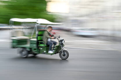 Trotočkaš se kreće ulicom. Zamućena fotorfija vozila na ulici u gradu.