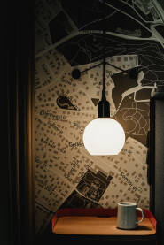 Lampa Detalji enterijera hotelske sobe. Lampa koja obasjava mapu grada Budimpešte i šoljicu kafe.