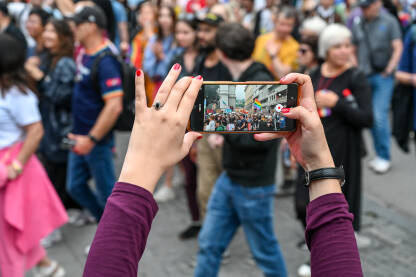 Mediji o LGBT zajednici/Povorka ponosa u Sarajevu Žena snima događaj mobilnim telefonom. Djevojka mobilnim telefonom snima grupu ljudi na protestu.