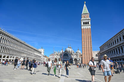 Venecija, Italija: Ljudi šetaju glavnim trgom. Piazzetta San Marco. Popularna turistička destinacija. Zvonik, Bazilika svetog Marka i Duždeva palača u centru grada.