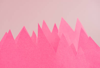 Papirne planine Roze papiri u obliku vrhova planina ispred pozadine.