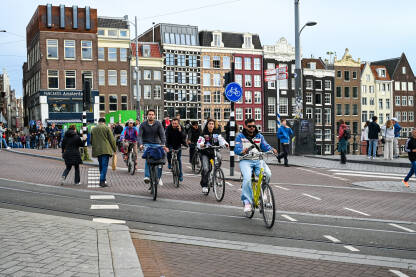 Ljudi voze svoje bicikle ulicom. Amsterdam, Nizozemska: Ljudi na biciklima. Biciklisti voze bicikle ulicom. Vožnja biciklom u gradu.