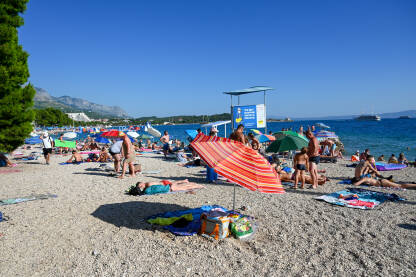 Turisti u Makarskoj, Hrvatska Ljudi uživaju na plaži. Turisti se sunčaju na pješčanoj plaži. Ljetni odmor.