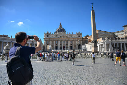 Vatikan: Ljudi na Trgu svetog Petra. Bazilika Svetog Petra. Turisti istražuju Rim i Vatikan.