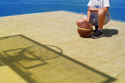 Dječak na košarkaškom terenu sa lpotom.