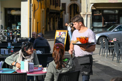 Konobar uslužuje goste Konobar uslužuje goste u kafiću.