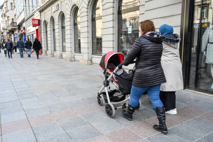 Mlade majke sa dječjim kolicima. Mlade majke sa dječjim kolicima. Mame i bebe. Žena gura dječja kolica u gradu. Roditelji šetaju ulicom. Roditeljstvo.