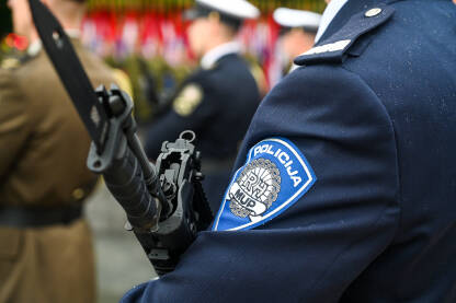 Policija, Hrvatska. Policajac drži pušku dok stoji u formaciji na ulici. Grb hrvatske policije. Hrvatske policijske snage.