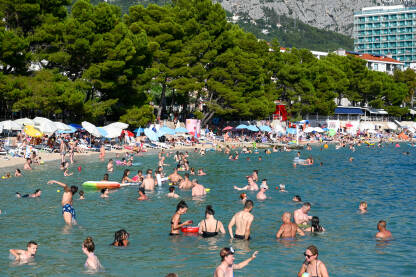 Ljudi se kupaju i sunčaju Turisti na moru. Ljudi se kupaju i sunčaju u Jadranskom moru. Ljetni odmor. Grupa turista na plaži tokom toplog ljetnog dana. Makarska, Hrvatska.