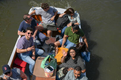 Turisti na brodu istražuju grad. Turisti na brodu istražuju grad. Grupa ljudi na čamcu na rijeci.