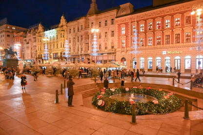 AK1_2244a Advent u Zagrebu, Hrvatska. Ukrasi s lampicama na glavnom gradskom trgu. Ljudi se zabavljaju na Adventu na trgu baja Jelačića noću. Fontana Manduševac.