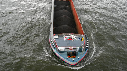 Barža natovarena ugljem na rijeci. Riječni transport robe. Teretna barža.