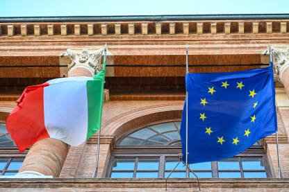 Italijanska i zastava Evropske Unije Italijanska i zastava EU se vijori na vjetru. Zastava Italije i Europske unije vijori se na zgradi. Simbol Italije i EU.