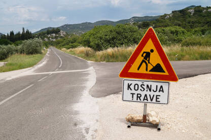 Znak za košnu trave na putu na praznoj cesti.